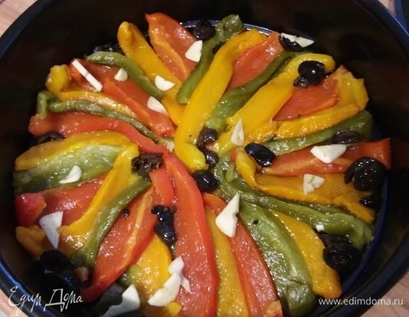 Перец болгарский запечь в духовке при температуре 200°С до черных подпалин, охладить немного и снять кожицу. Разрезать на полоски. Разъемную форму смазать оливковым маслом. Посыпать щепотками: розмарина, тимьяна и сахара. Выложить полоски перца. Выложить пластинки чеснока и кусочки маслин без косточки. Посолить и поперчить.  