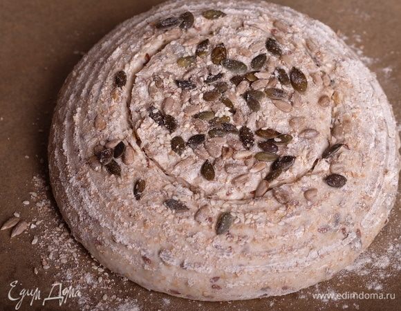 Примерно за 1,5 часа до выпечки хлеба начать разогревать духовку вместе с колпаком для выпечки или противнем (см. ниже п. 18 — как организовывать пар в духовке) до максимальной температуры. Запомните, что главное в выпечке хлеба — это жар и пар. Выжмите из своей духовки максимум. Моя разогревается до 250°С. Минимум для выпечки хлеба — 230°С. Если ниже — красивый хлеб может не получиться, надрезы не раскроются, корка будет бледной и «вялой». Как организовать пар? Можно использовать колпак для выпечки — это либо специальный набор (например, от Emile Henry), либо утятница с плоской крышкой, либо толстостенная металлическая кастрюля и камень для выпечки. Вообще, без камня для выпечки сложно получить ровный, хорошо пропеченный хлеб с красивой корочкой. Если не можете приобрести колпак, то камнем все же рекомендую обзавестись. Также пар можно сделать другим способом — начать разогревать духовку вместе с противнем (либо небольшой сковородкой, установленной на самое дно духовки). После того, как хлеб скидывается в духовку на камень, без промедления сразу же на раскаленный противень или сковородку выливается 1 стакан кипятка. Начнется активное испарение воды. Не обожгитесь только, будьте осторожны! Итак, перенести расстоенную заготовку на бумагу для выпечки, сделать надрез или надрезы. Я сделала для круглого хлеба 1 надрез лезвием по кругу.