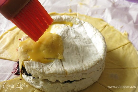 Поднимаем тесто по сегментам на сыр. Смешиваем желток с ложкой молока и смазываем тесто.
