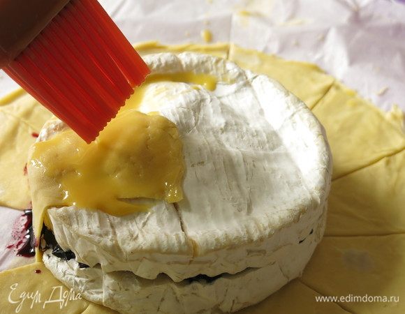 Поднимаем тесто по сегментам на сыр. Смешиваем желток с ложкой молока и смазываем тесто.