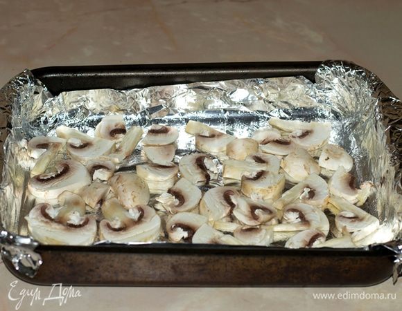 На противень выложить фольгу и смазать маслом. (Фольга не из-за требований рецепта, а для облегчения мытья). Шампиньоны нарезать и выложить на противень.