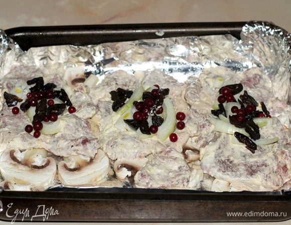 Выложить свинину. Нарезать лук и чернослив. Выложить поверх свинины.
Добавить по чайной ложке брусники на каждый кусок.