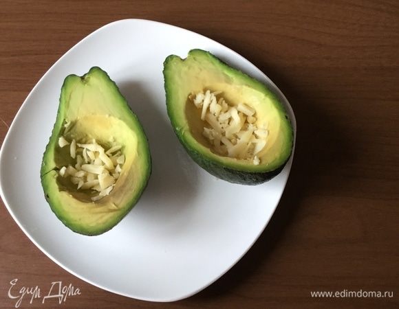 На дно авокадо кладем немного нарезанного сыра.