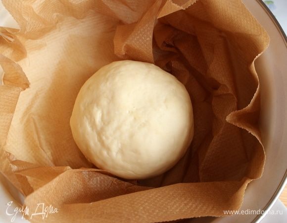 В кастрюле, закрытой крышкой, вскипятить воду, вылить воду, она нам не понадобится. Вытереть насухо кастрюлю и крышку. Застелить кастрюлю бумагой для выпечки. Тесто положить в горячую сухую кастрюлю на бумагу для выпечки, закрыть горячей крышкой и оставить на 30 минут. Оно приобретает дополнительную эластичность и мягкость.