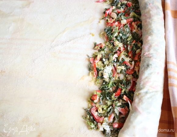 Штрудель скатать рулетом, начиная со стороны, где лежит начинка, подталкивая рулет скатертью, на которой лежит тесто.