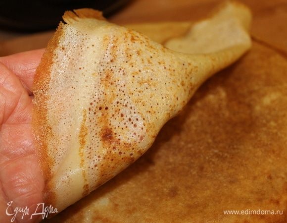 Как только начинают румянится края, можно перевернуть блинчик и поджарить с другой стороны. Не переживайте, они не будут рваться, потому что за ночь клейковина в муке достаточно хорошо разбухнет, и тесто обретет ту необходимую структуру, которая не позволит им рваться. Блинчики складывайте в стопочку и накрывайте их крышкой, чтобы они оставались мягкими и не теряли влагу.