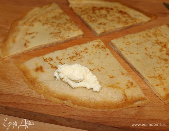 Творог протрите через сито, добавьте сахар, ванилин и распаренный изюм, который лучше нарезать маленькими кусочками. Берите сразу несколько испеченных блинчиков, разрежьте на 4 части и на каждую четвертинку положите по 1 ч. л. начинки. Начинка может быть любая — мясная, грибная, но сегодня будет творог.