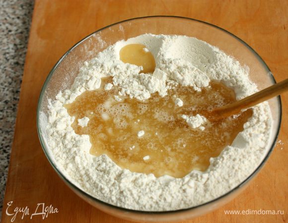В большую миску просеять муку и 1 ч. л. соли. Добавить в муку горячую смесь и энергично перемешивать деревянной ложкой, собирая в шар. Яйцо в тесто не добавляется, оно только для смазывания.