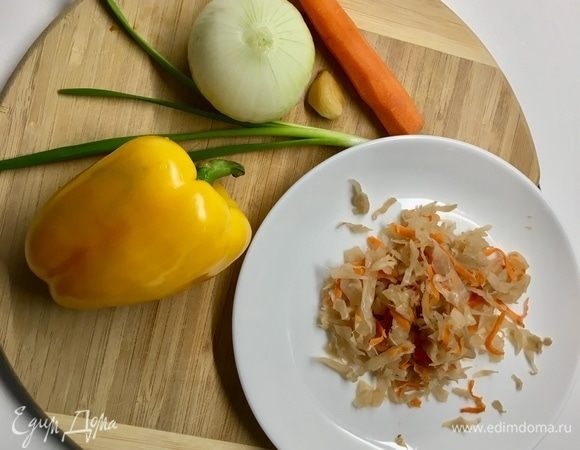 Подготовим овощи для супа. Чистим среднего размера луковицу, морковку и дольку чеснока. Моем и обсушиваем болгарский перец и веточку зеленого лука. Домашняя маринованная капуста очень удачно вписалась в рецепт.