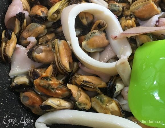 В разогретую сковороду налить немного подсолнечного масла, выложить чеснок и слегка его припустить. Добавить отварные очищенные мидии и нарезанные кальмары. Хорошо прогреть их в чесночном масле.