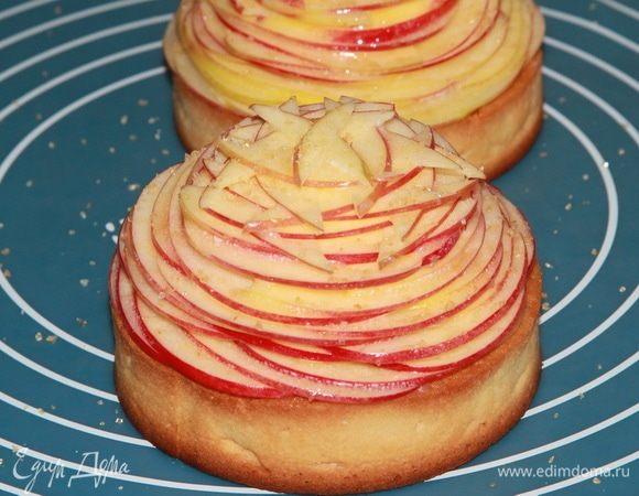 Выкладываем яблочные пластинки по спирали, начиная от края и заканчивая в центре. Смазываем обильно растопленным сливочным маслом и посыпаем карамелизированным сахаром. Или просто коричневым сахаром. Выпекаем при 175°С 10-12 минут.