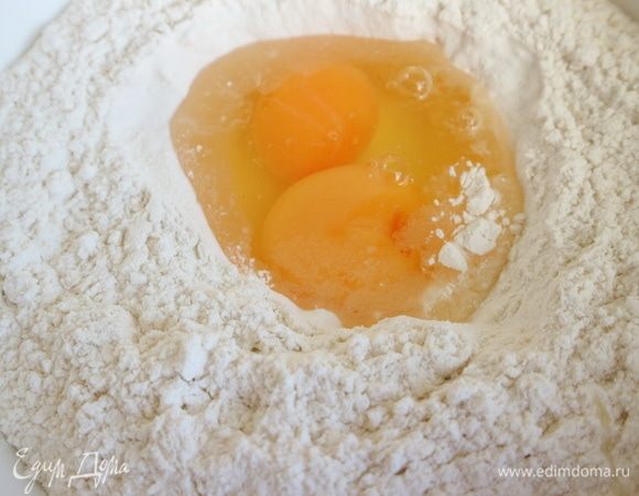 Замесить тесто. В воронку в центре муки, в которую добавлена соль, поместить яйца, добавить немного воды, перемешать, добавляя оставшуюся воду. 