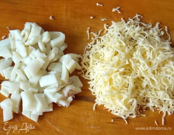 Сыр нужно натереть на мелкой терке, вареные кальмары порезать.
