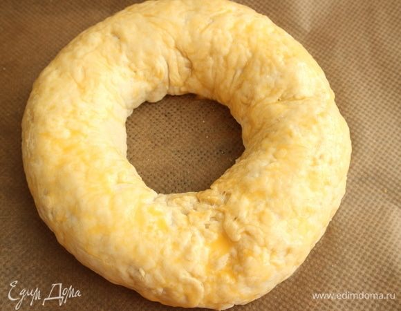 Положить на смазанный оливковым маслом и накрытый бумагой для выпечки противень.  Желток взбить с молоком, смазать пирог кисточкой этой смесью. 