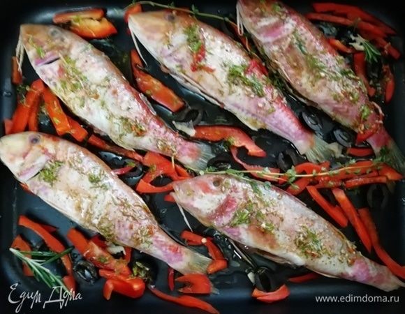 Выложите болгарский перец и маслины к барабульке. Каждую рыбу смажьте маринадом и оставьте на 10 минут. Затем поставьте противень в разогретую до 180°С духовку.