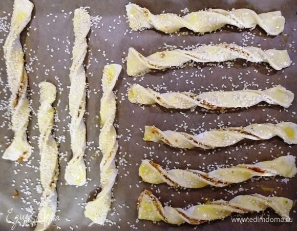 Укладываем жгуты на противень, смазываем желтком и посыпаем кунжутом. Ставим в разогретую до 200°С духовку на 10 минут.