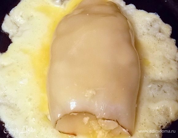 Сковороду хорошенько нагреть, смазать маслом и вылить на нее перемешанное вилкой соленое яйцо. И сразу кладем на середину один кальмар.