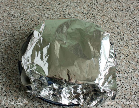 Сверху поместить большой кусок фольги, закрывающий тыквенные ломтики полностью. Из противня слить масло, протереть его бумажным полотенцем и вернуть в духовку. Над ним вновь поставить пирог и продолжить запекание. Через 40 минут фольгу аккуратно снять и запекать еще 25 минут. Духовку выключить, но пирог оставить в ней на 1 час, затем вынуть и полностью остудить при комнатной температуре.