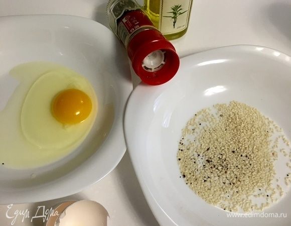 Приготовим кляр. С таким вариантом кляра я пробовала саганаки несколько лет назад в Греции, он мне очень понравился, поэтому рассказываю и вам. В одну мисочку разбиваем яйцо. В другую мисочку — горсть кунжутного семени, немного свежемолотого перца и пару столовых ложек кунжутного масла. Яйцо разбить вилочкой. Я не солила, решив что сыр сам по себе соленый. И, на мой вкус, это было правильно. Итак, сначала обмакиваем сыр в яйцо, затем — в кунжутно-масляную смесь, и на сковороду.