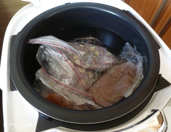 В мультиварку налить теплой воды. Кладем пакеты с мясом. Вода должна покрывать их. Остатки воздуха поднимаются вверх, значит, ничего не мешает куриной грудке готовиться равномерно.