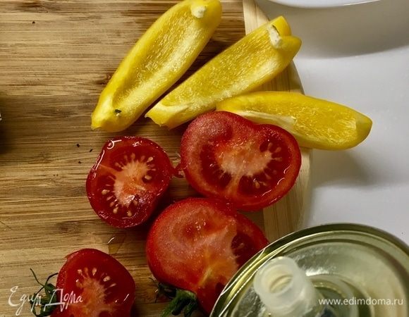 Помидоры разрезаемых пополам, срез сбрызгиваем оливковым маслом. Перчик освобождаем от семян и режем полосочками.