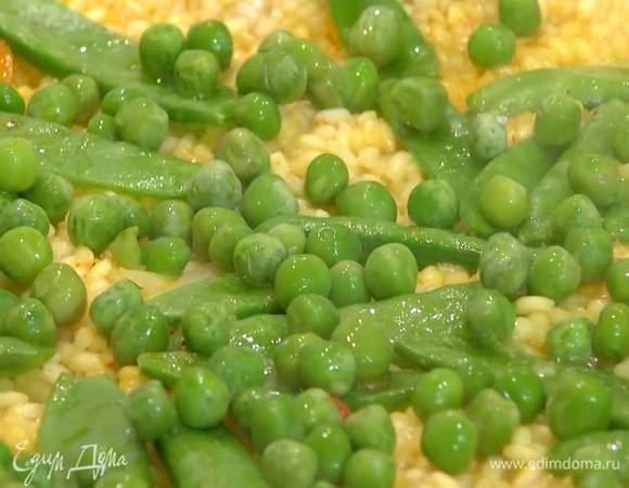 Добавить в паэлью размороженный горошек, помидоры, артишоки и прогревать еще 2 минуты, затем выключить огонь, накрыть сковороду крышкой и оставить на 10 минут.