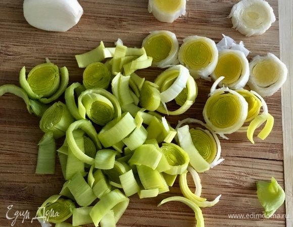 Теперь подготовим овощи. Лук-порей, более нежный и деликатный, чем лук репчатый, поэтому будет намного уместнее с нежной овсянкой использовать именно его. Нарежем светлую часть лука-порея колечками. Одну дольку чеснока почистим, раздавим плоской стороной ножа и измельчим.