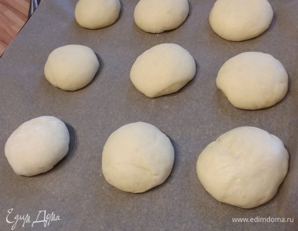 Сформировать круглые булочки и выложить на противень, покрытый пергаментной бумагой. Накрыть полотенцем и отправить в теплое место на 30 минут для дальнейшей расстойки. 
