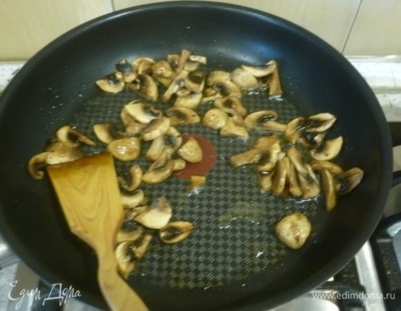 В сковороде разогреть масло. Грибы нарезать пластинами, выложить в сковороду. Раздавить к ним зубчик чеснока. Жарить до испарения жидкости.