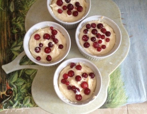 Смажьте порционные формочки сливочным маслом, посыпьте мукой, разложите в них творожную массу, сверху выложите ягоды клюквы.