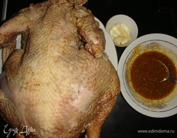 Курицу помыть, обсушить бумажными полотенцами. Чеснок разрезать пополам, сделать надрезы в тушке и нашпиговать их чесноком. В маленькой миске смешать кориандр, соль, черный перец, мускатный орех, паприку, куркуму. Влить яблочный уксус, белое сухое вино и оливковое масло. Все тщательно перемешать. 