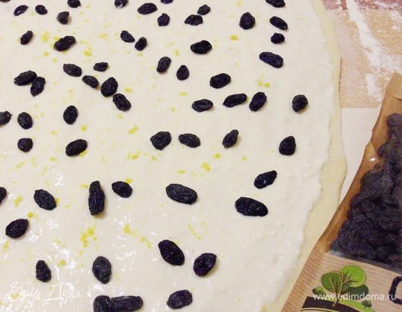 Изюм ополоснуть водой. Посыпать начинку цедрой с одного лимона и подготовленным изюмом.