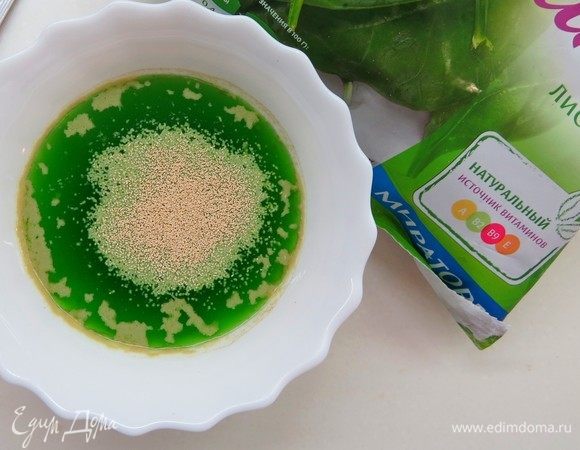 Готовим шпинатные блинчики. Шпинат выложить в чашу блендера, залить 125 мл теплой воды, пробить блендером до однородности, полученную смесь процедить сквозь мелкое сито. В теплый шпинатный сок (125 мл) кладем пол чайной ложки сухих дрожжей и сахар. Оставляем на 5–10 минут. На фото зеленый цвет такой насыщенный, потому что я не удержалась и капнула зеленый краситель. От этого шага можно вполне воздержаться.