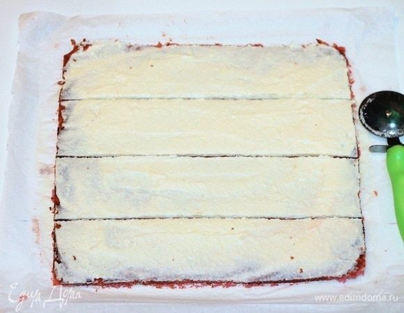 Когда корж остынет, переверните его. Обрежьте с помощью линейки сухие и неровные края, разделите на 4 части и смажьте кремом.