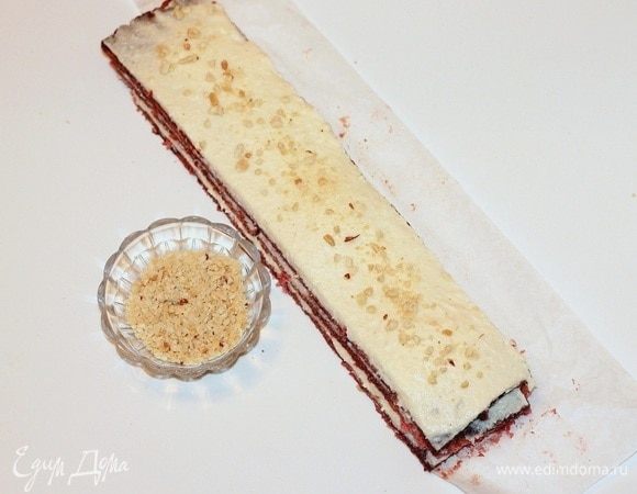 Складываем 3 коржа стопкой. Каждую смазанную полоску посыпаем измельченными орешками.
