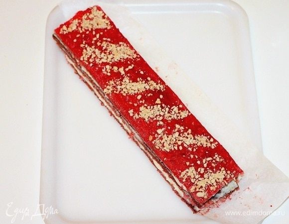 Последнюю полоску кладем так, чтобы верх был без крема. Верхнюю полоску можно немного смазать (слегка) малиновым джемом и посыпать орешками. Разрезаем полоску на части и кладем пирожные на блюдо.