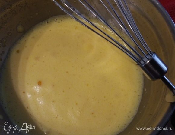 В большую миску поместить желтки и добавить 5 ст. л. теплой воды. Взбить до увеличения массы в объеме во много раз и консистенции пены. Добавить цедру апельсина. 