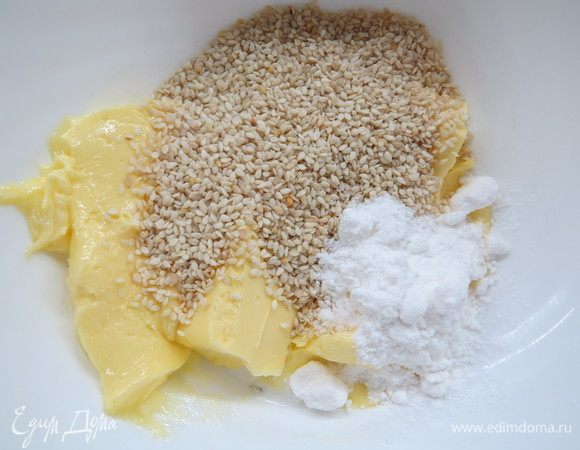 В миске смешать слегка растопленное масло с разрыхлителем и 4 ст. л. сахарной пудры, затем добавить кунжут. Вымесить до однородности.