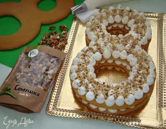 На нижний корж уложить еще один корж и повторить процесс — крем и орешки.