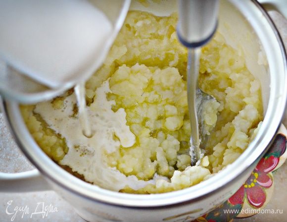 Слить воду, добавить к овощам теплое молоко и оливковое масло. Хорошо взбить с помощью толкушки.