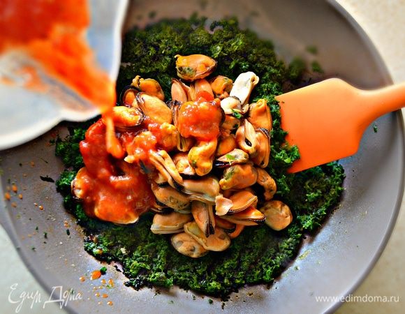 На оливковом масле обжарить раздавленные зубчики чеснока, затем вынуть чеснок, он больше не пригодится. К маслу добавить шпинат, протушить 5 мин., постоянно помешивая. Затем добавить томатный соус и мидии, приправить солью и перцем, тушить еще 5 мин., не забывая помешивать.