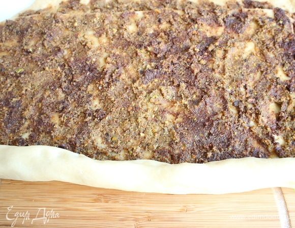 Выложить на тесто ровным слоем начинку, отступая от краев 2 см. Свернуть тесто плотно в рулет по длинной стороне. 