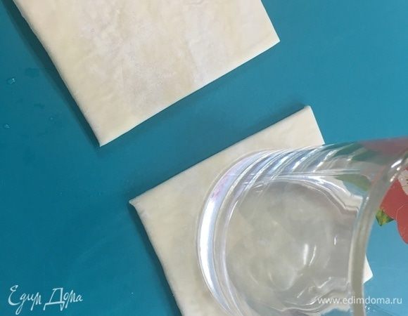 Слоеное тесто разрезать на порционные квадраты. Дном кружки немного примять середину. Выложить их на противень застеленный пергаментом и поставить в разогретую до 180°С духовку на 15 минут.