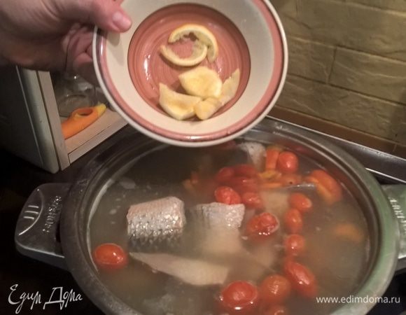 Теперь сливаем бульон из лука обратно в уху. Туда же возвращаем мясо из рыбьих голов. Если в процессе у вас выкипело много жидкости, доливаем воды. Это не обязательно, но я бросаю в уху отжатые лимонные дольки, они придают пикантность аромату.