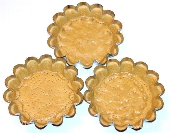 У меня металлические формочки, маслом не смазывала, но немного посыпала дно  измельченной печенюшкой. Из остатков теста формируем бортики тарта (h=3). Прокалываем тесто вилкой. Убираем заготовки в морозильную камеру на час. Диаметр дна формочек 12 см.