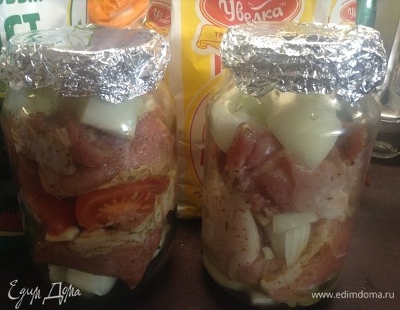 Мясо (свинина, баранина, говядина — что душе и небу угодно. На говядину — время чуть больше готовки, всего-то), у нас была свинина.
Помыли, салфеткой обсушили, нарезали крупно (в полкулака).
Нарезали крупно лук и помидор, почистили чеснок на зубчики целые.
В обычные банки стеклянные (для заготовок, 1 или 1,5 л объема) складываем вперемешку лист лавровый, дольки лука и зубчики чеснока, перец душистый горошком, мясо кусочки, дольки помидора (можно в оду банку класть его, в другую — нет), солим и перчим свежеподавленным и протертым черным перцем горошком. 
Сверху банки закрываем фольгой в несколько слоев, прижимаем краешки к банке по ободку, никаких дырок специальных сверху не нужно, избытки пара сами выйдут.