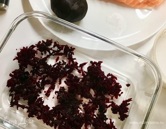 На мелкой терке натереть свеклу. Берем форму, где будем мариновать рыбу. Сначала припорошим дно формы свеклой.