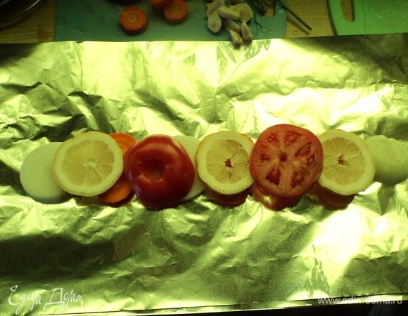 На фольгу разложили нарезанные помидоры, лимон, лук-репку.