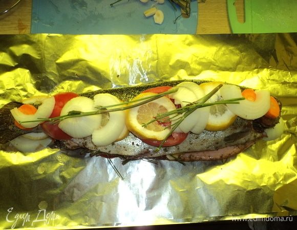Сверху на рыбу также уложили нарезанный помидор, лук-репку, лимон, можно и веточки зелени.