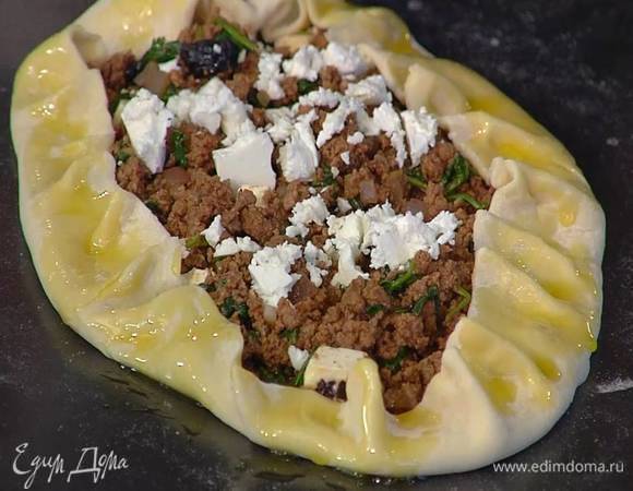 Разложить на лепешки начинку, оставив края теста свободными, сверху покрошить оставшуюся фету, затем завернуть свободные края теста на начинку, защипнуть их, смазать оставшимся оливковым маслом и выпекать в разогретой духовке 15 минут.